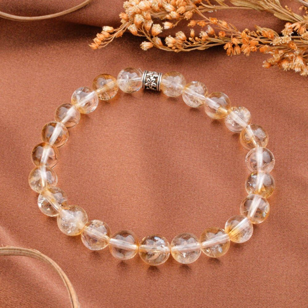 A 5A+ quality 8mm clear citrine beaded bracelet with a silver clasp, displayed on a brown silk fabric.