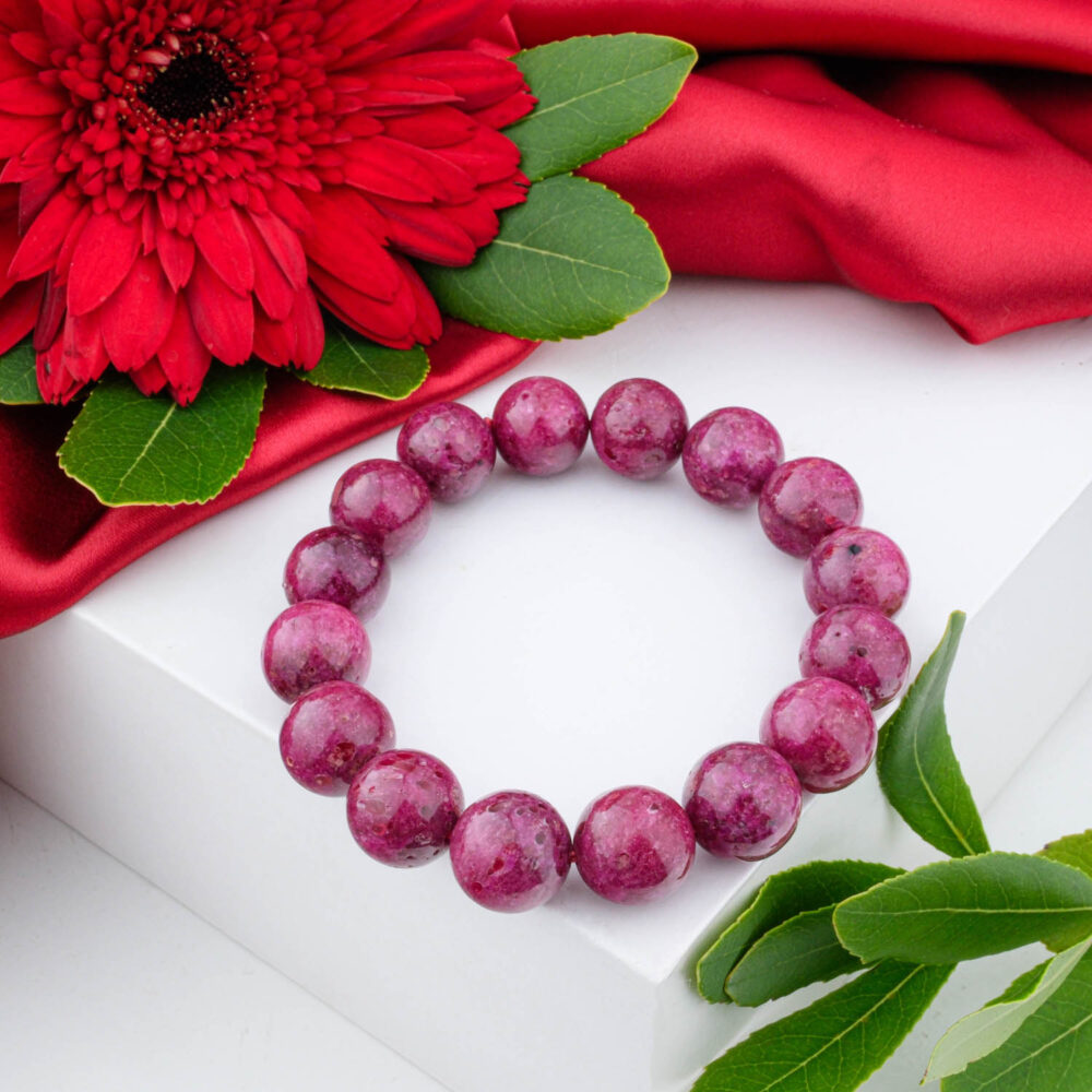 5A+ Grade Ruby bracelet with large 13-14mm polished pink-red beads, shown on a white box with a red flower.
