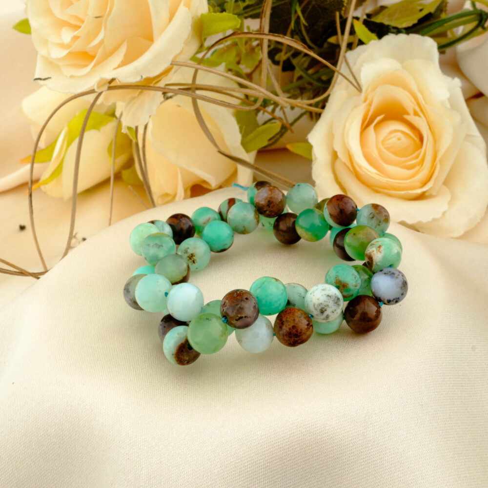 A AAAA quality 10mm natural chrysoprase bead strand showing green and brown matrix, on a cream fabric.