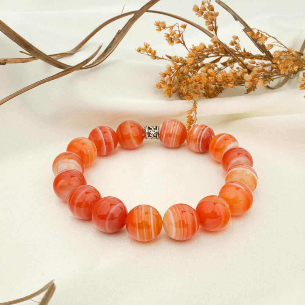 Banded agate 12mm beaded bracelet in warm orange on neutral fabric