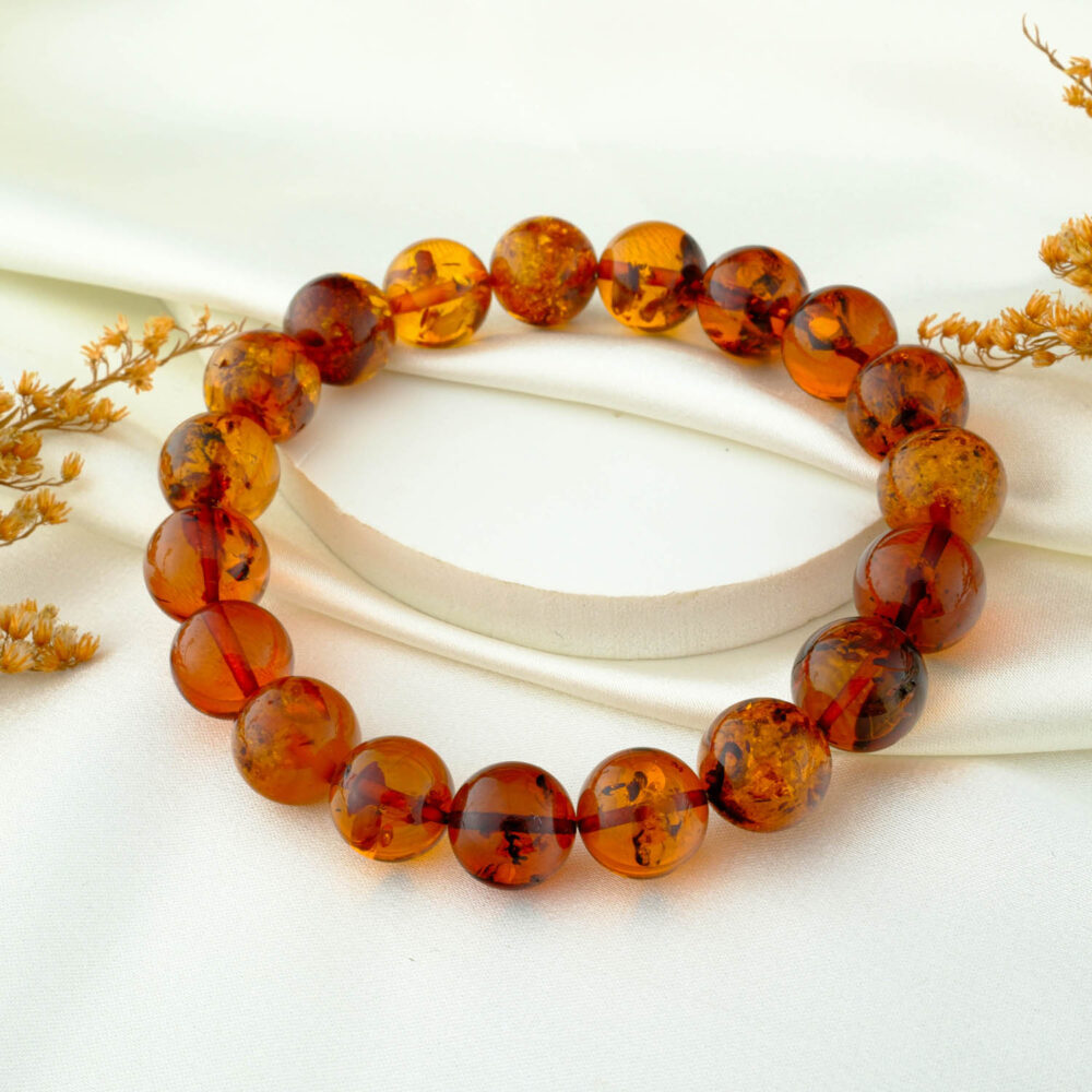 Certified amber bead bracelet with 11–12 mm round beads on neutral fabric