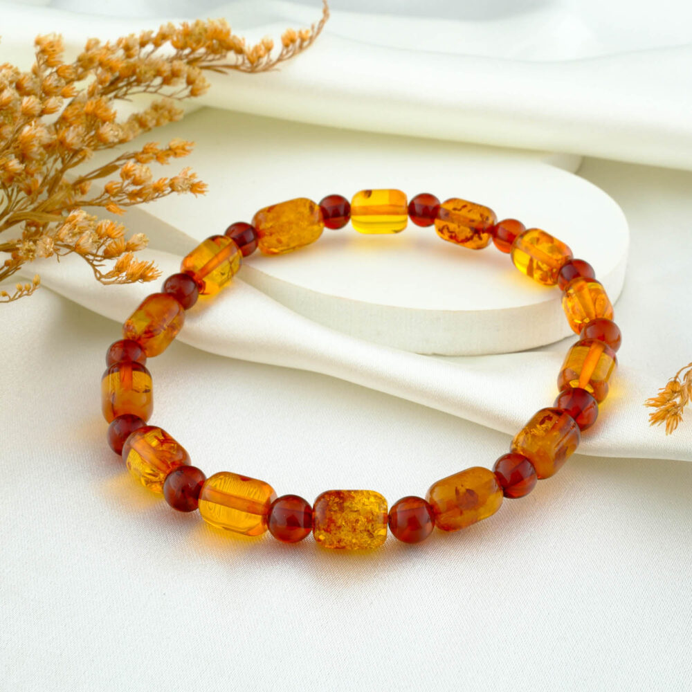 Certified natural amber capsule bracelet for adults in warm honey tone on neutral fabric