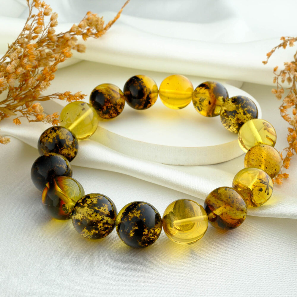 Certified adult amber bracelet with large 13–14 mm round beads in lemon and cognac tones on neutral fabric