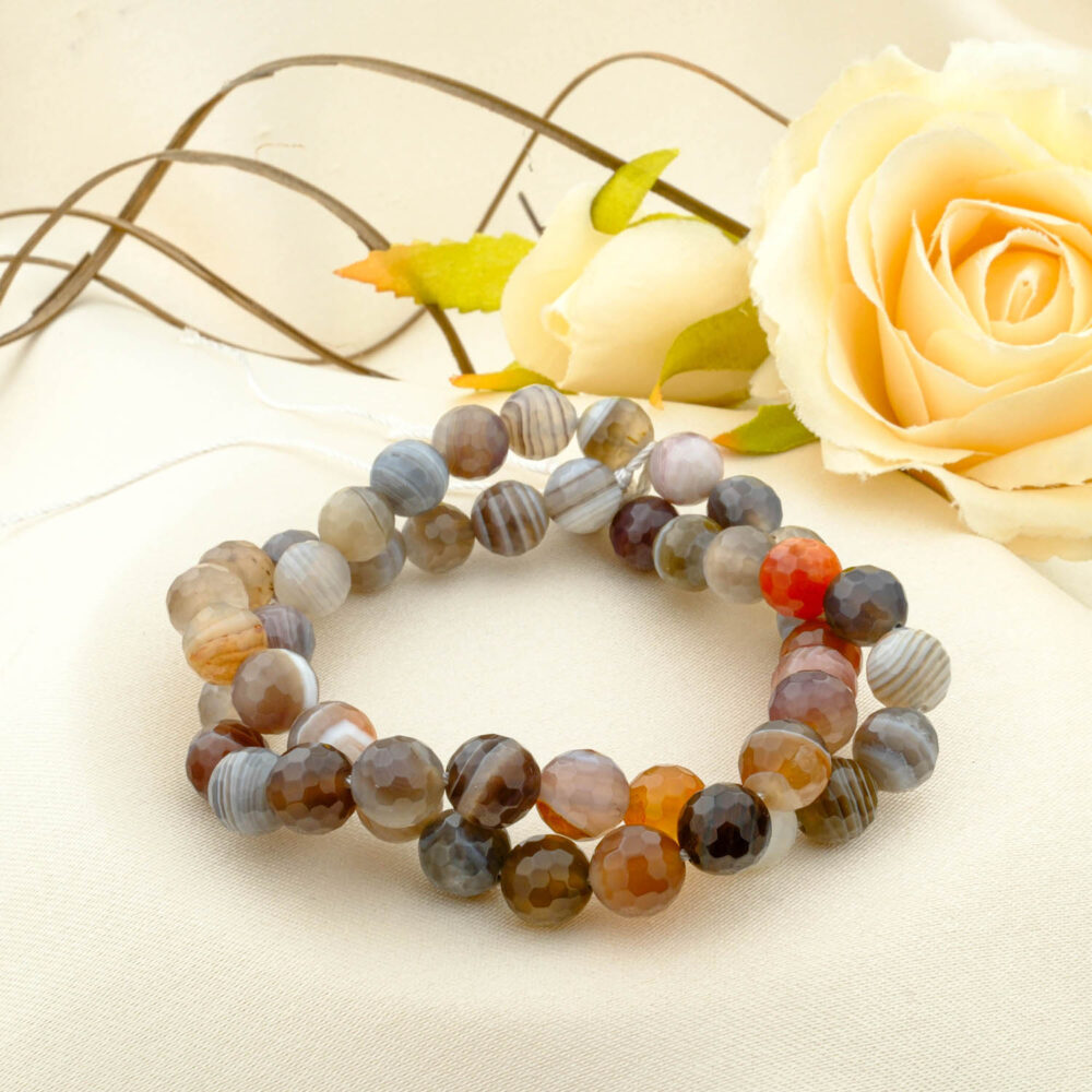 A double-wrapped strand of 8mm faceted Botswana agate beads with fine grey, brown, orange, and white bands.