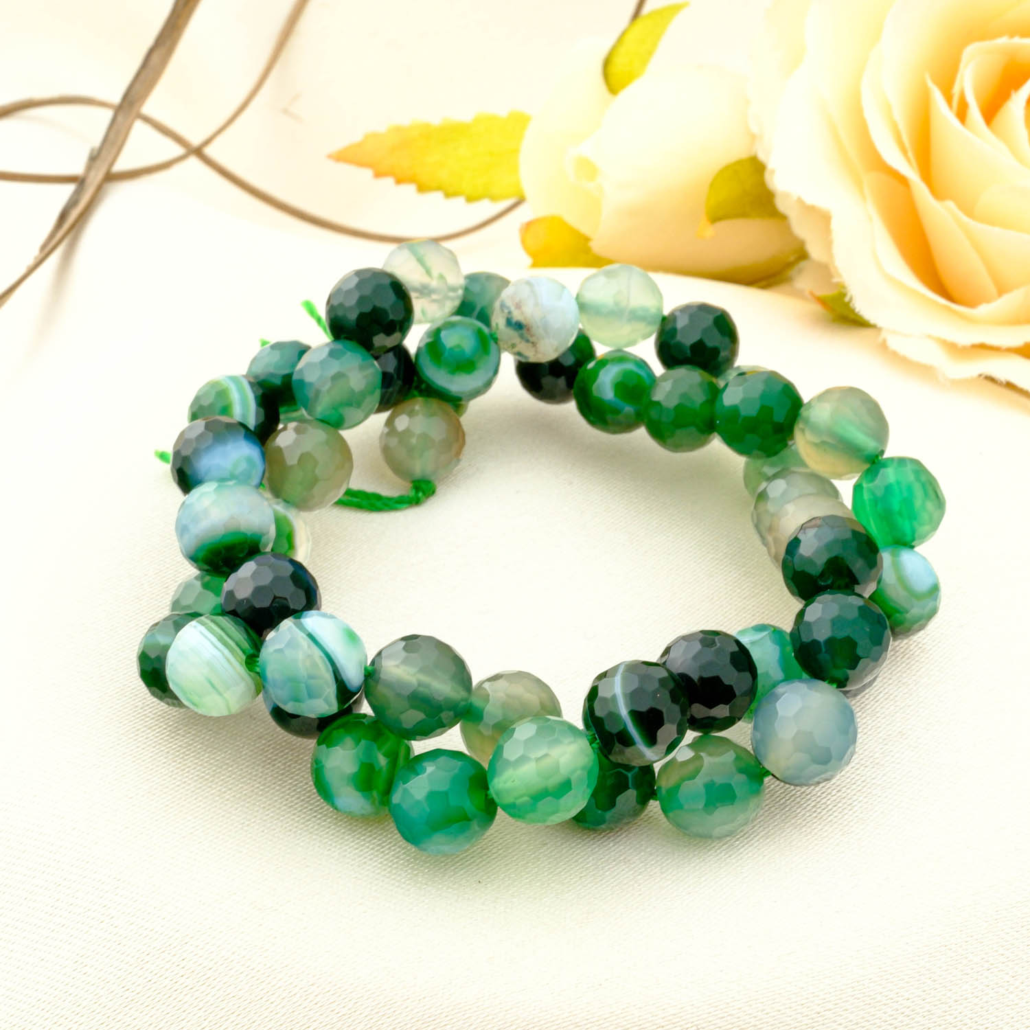faceted-green-madagascar-agate-beads-8mm A double-wrapped strand of 8mm faceted green Madagascar agate beads showing bands of dark green and milky white.