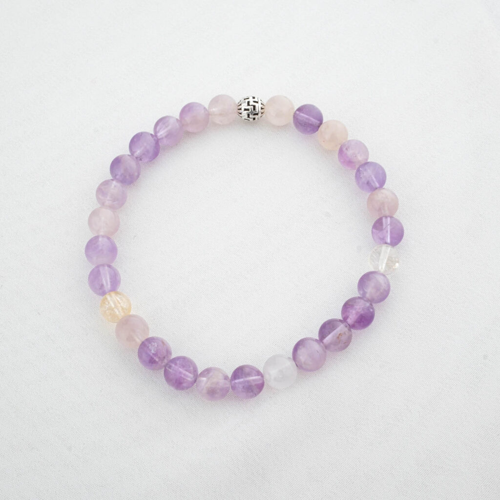 Pulsera de cornalina ágata natural de 6mm con cierre de plata, sobre tela de seda blanca y flores secas.