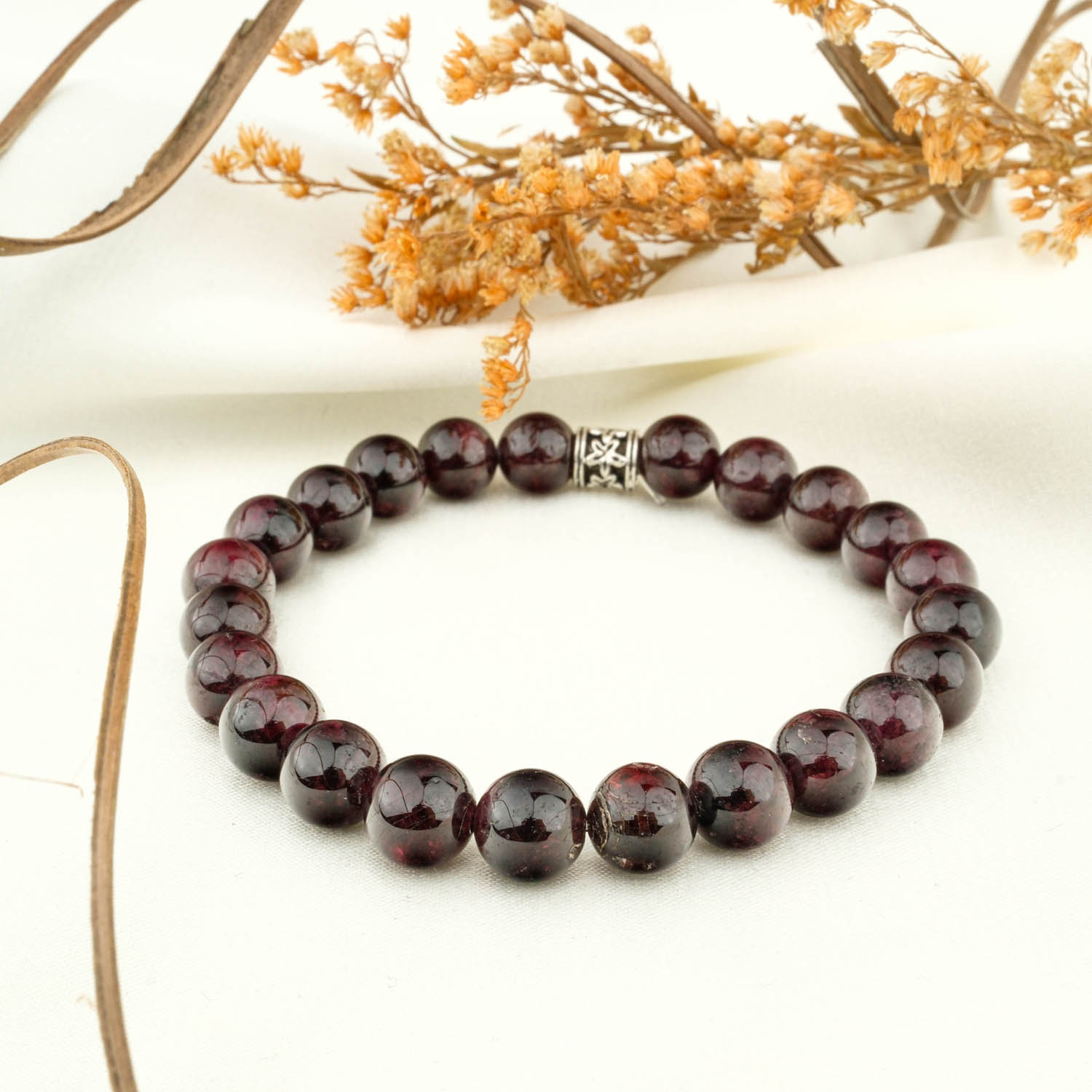garnet-8mm-deep-red-bead-bracelet Garnet 8 mm deep red bead bracelet with decorative spacer on light fabric