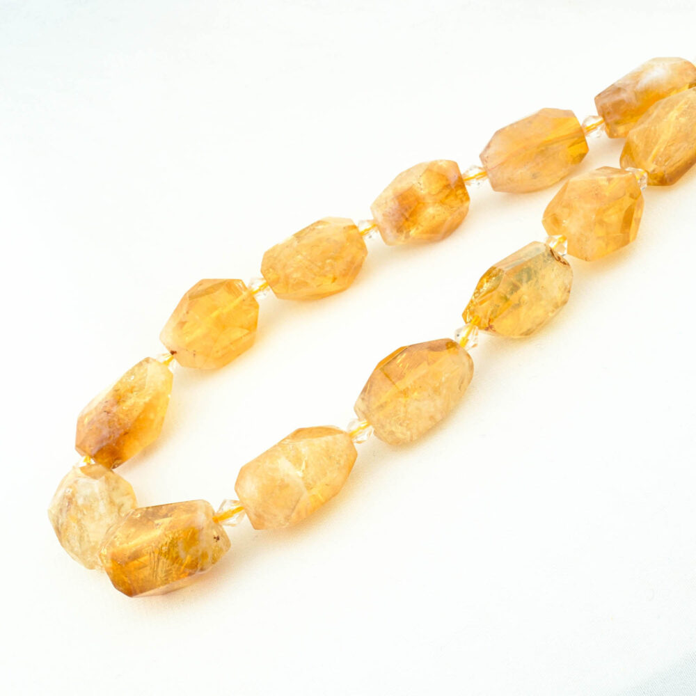 Hebra de cuentas de citrino en forma de pepita grande y facetada con un cálido color amarillo dorado.