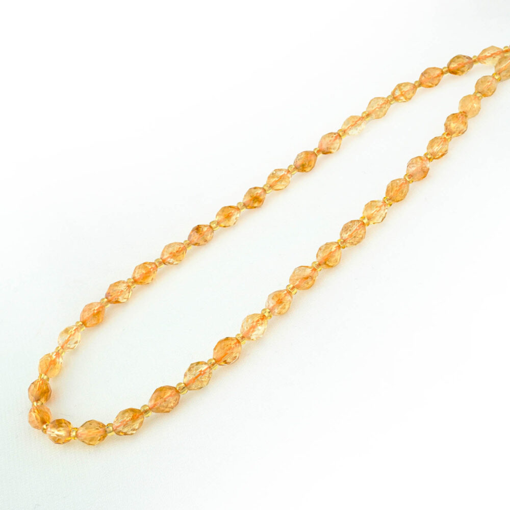 Hebra de cuentas de citrino ovaladas y facetadas con un cálido color amarillo dorado y acentos de oro.