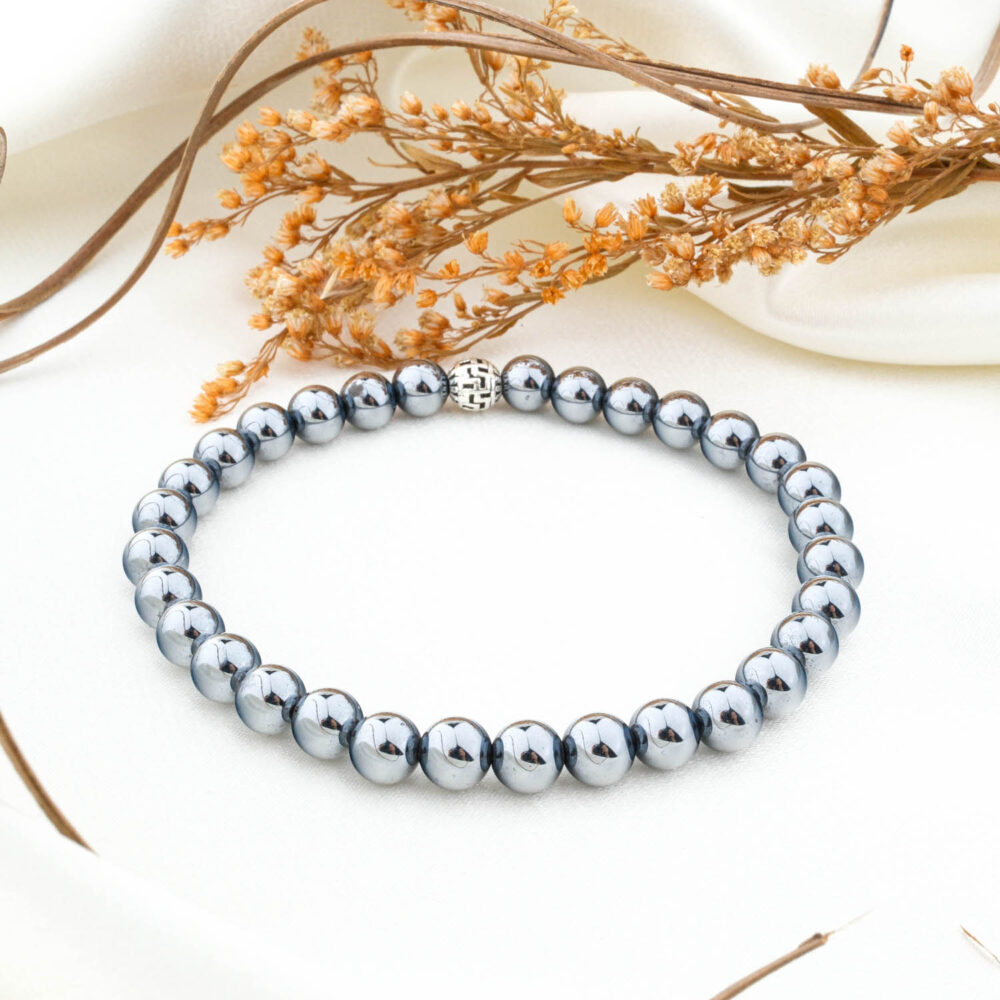 A natural 6mm blue goldstone beaded bracelet with a silver clasp, on a white silk fabric.