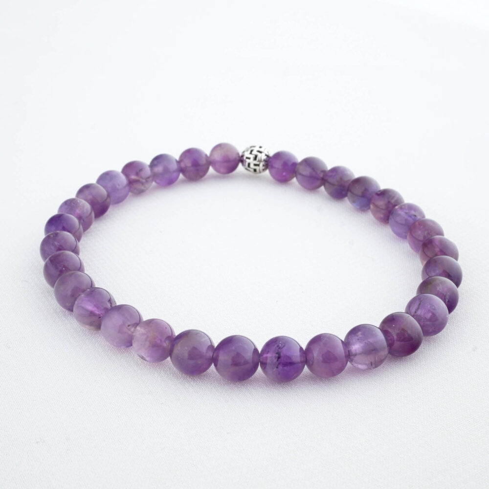 Close-up of a 6mm faceted citrine bracelet showing its golden-yellow color, on a white background with dried flowers.