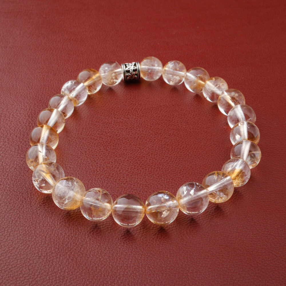 Pulsera de citrino claro de 8mm y calidad 5A, con un cierre de plata, sobre un fondo de tela de seda marrón.