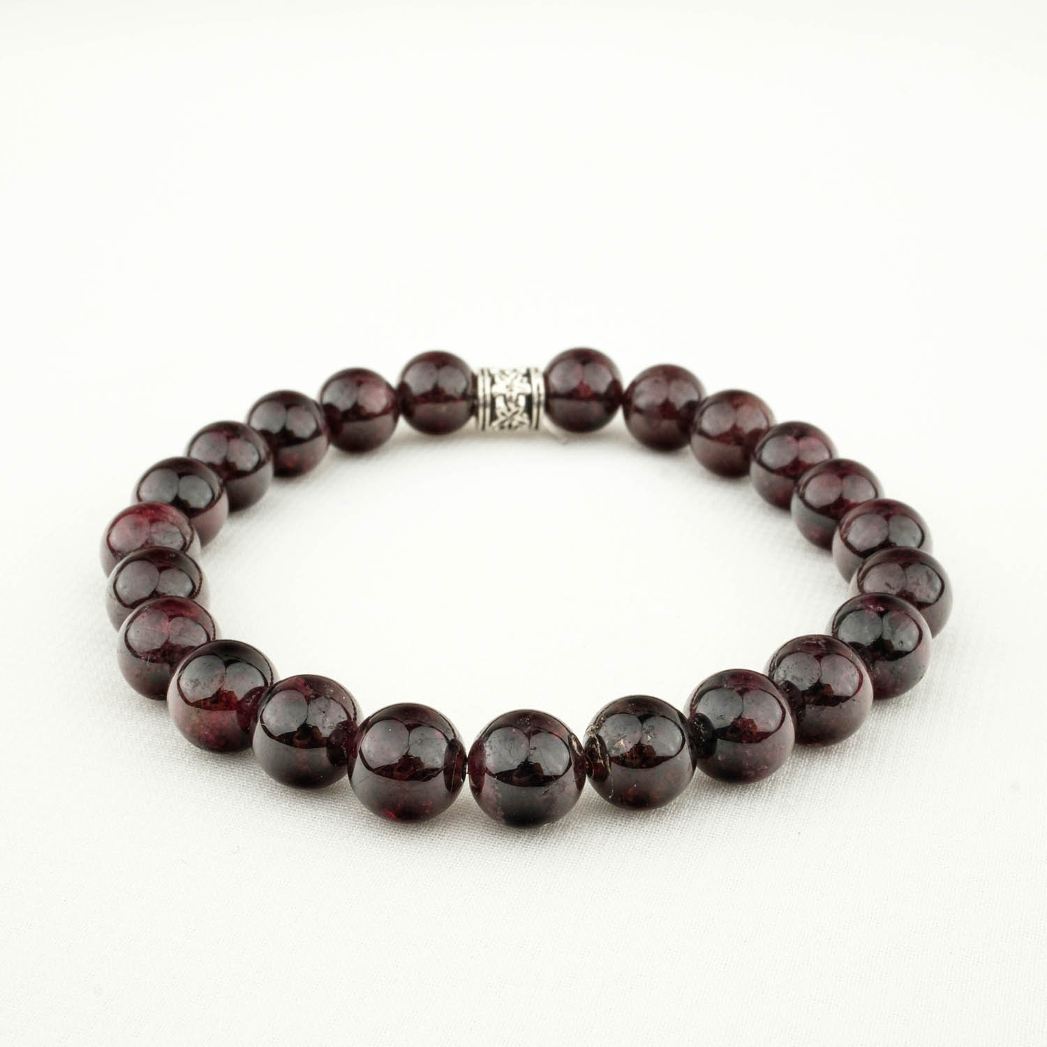 pulsera-granate-rojo-oscuro-8mm-cuentas Pulsera de granate rojo oscuro con cuentas de 8 mm y separador decorativo sobre tela clara