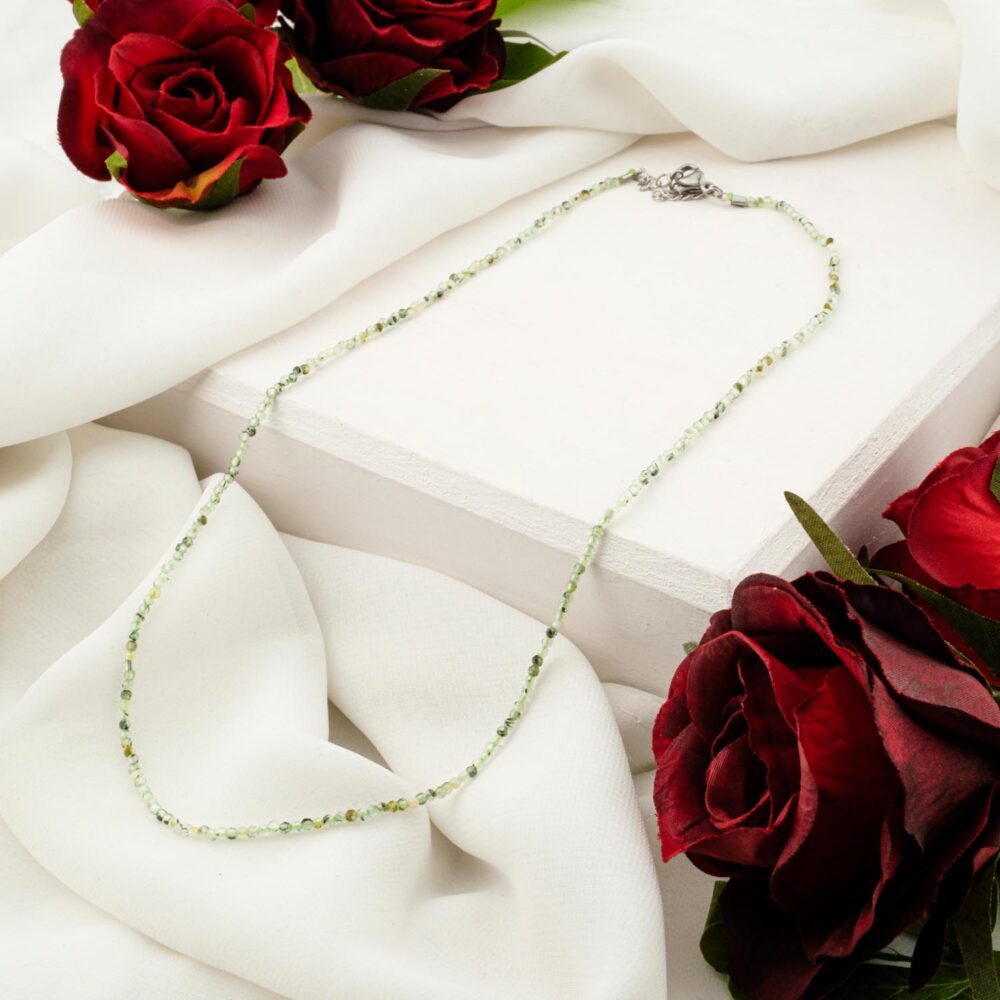 Delicate 1.5-2mm natural prehnite faceted bead necklace on white display