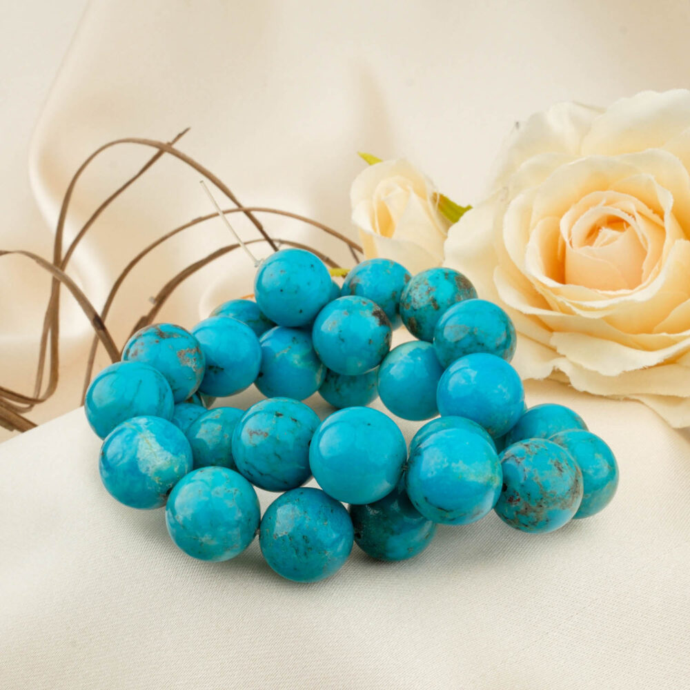 A strand of large 14-15mm 5A+ Grade Turquoise beads with natural matrix patterns on a cream fabric.