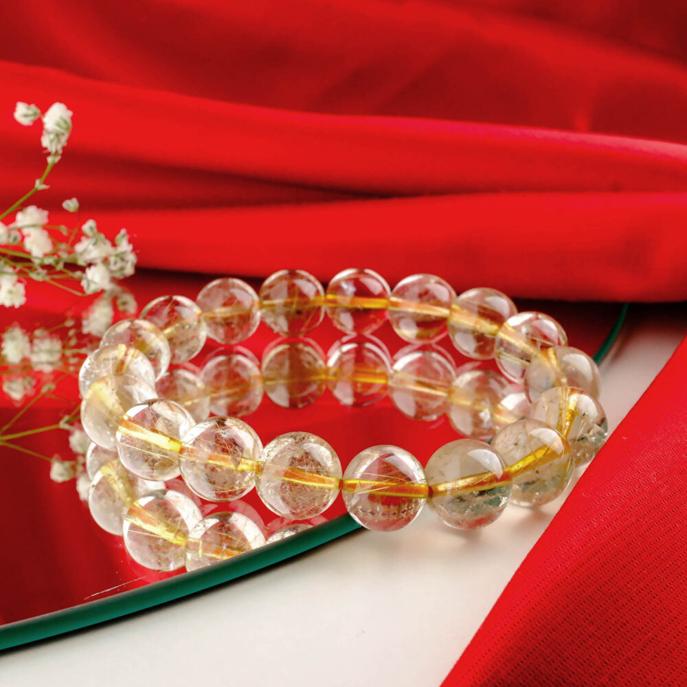 6A+ quality golden rutilated quartz bracelet with large 12-13mm "angel hair" beads on a red and white surface
