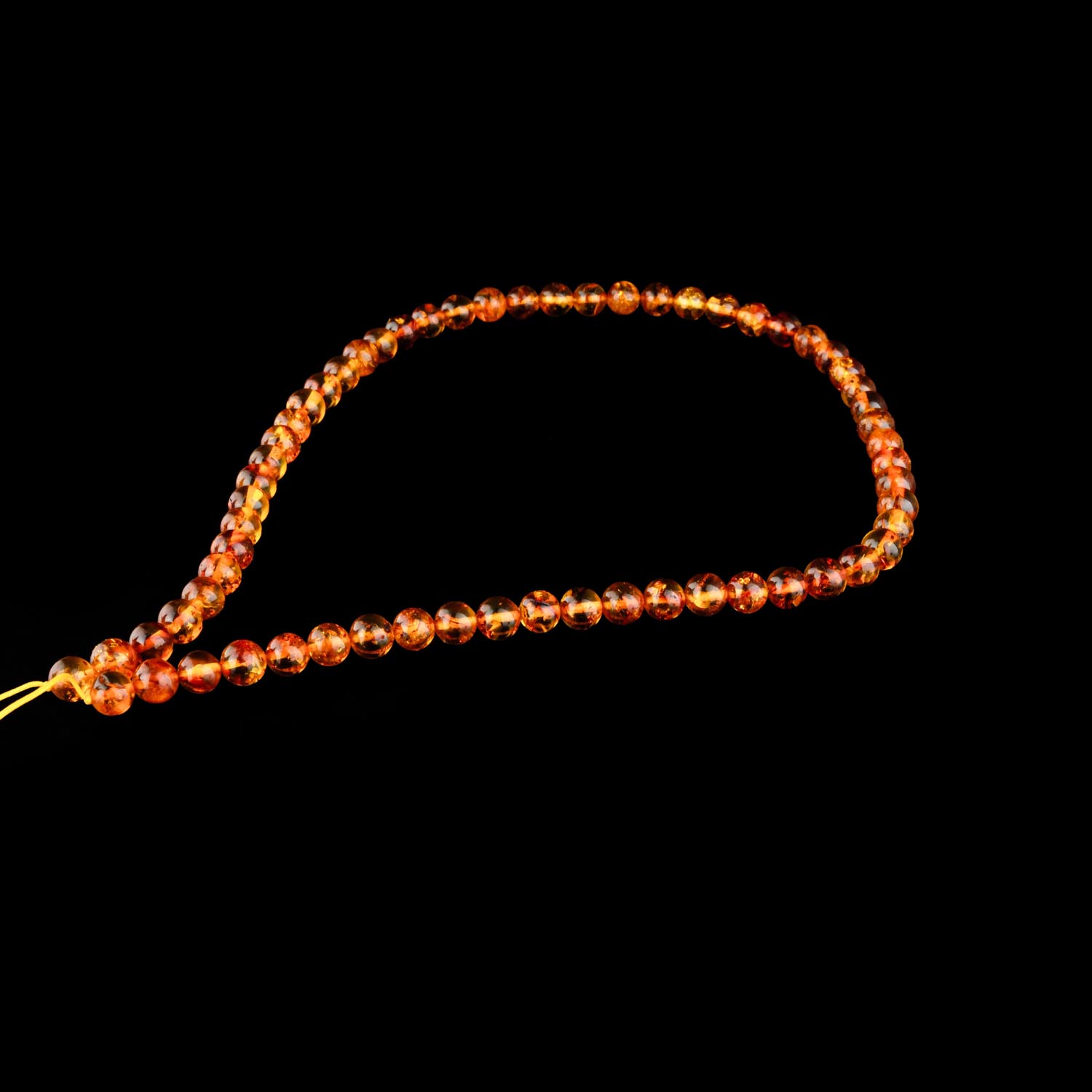 6mm-cognac-bernstein-strang Ein Strang aus 6-6.5mm polierten Cognac-Bernsteinperlen auf weißem Display