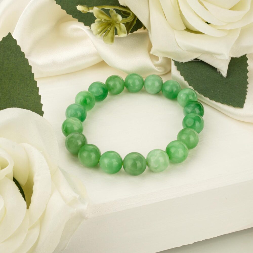 A 7A+ grade natural jade bracelet with large, 12-13mm vibrant green beads, displayed on a white textured surface.