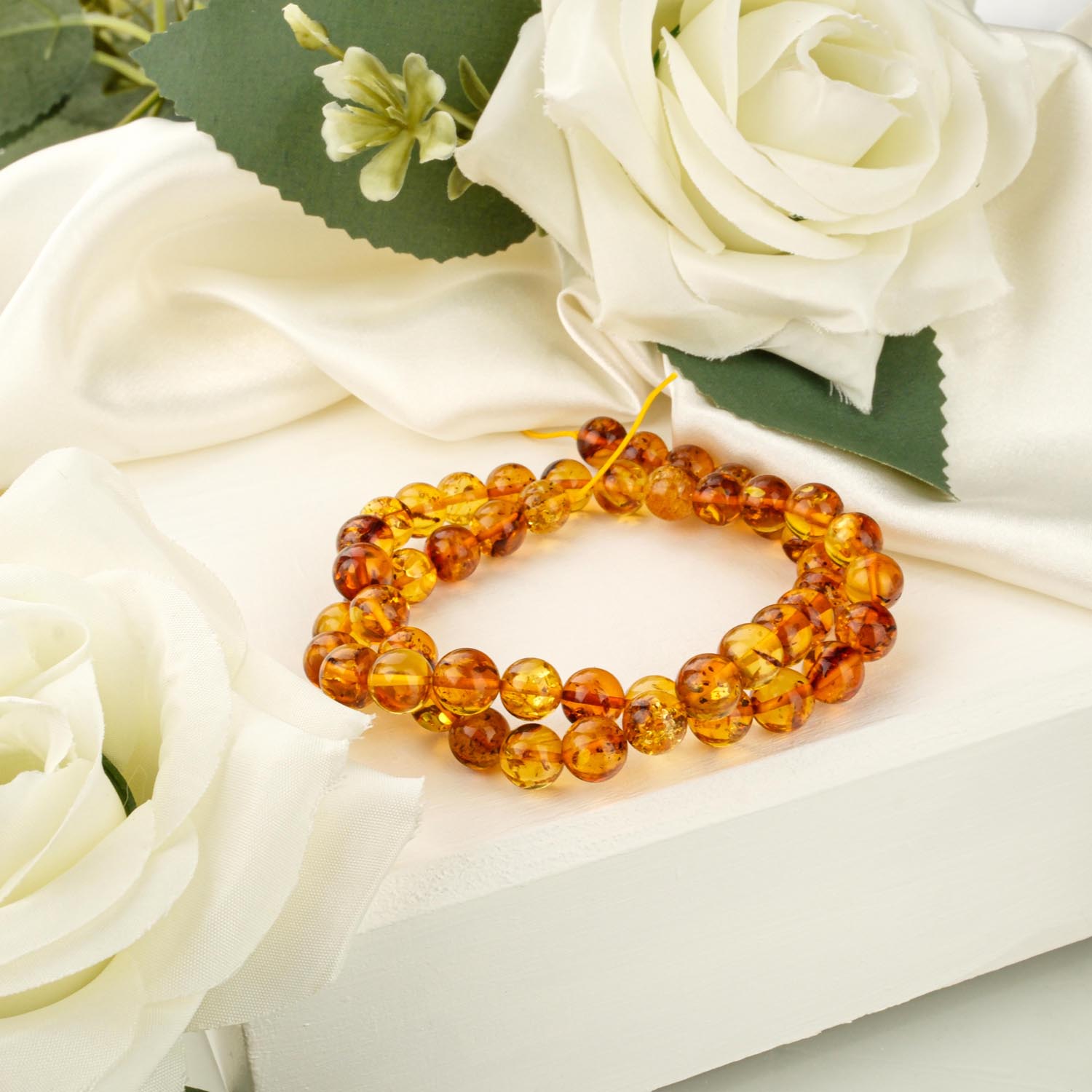 8mm-cognac-amber-bead-strand A strand of 8mm polished cognac amber beads on a white display