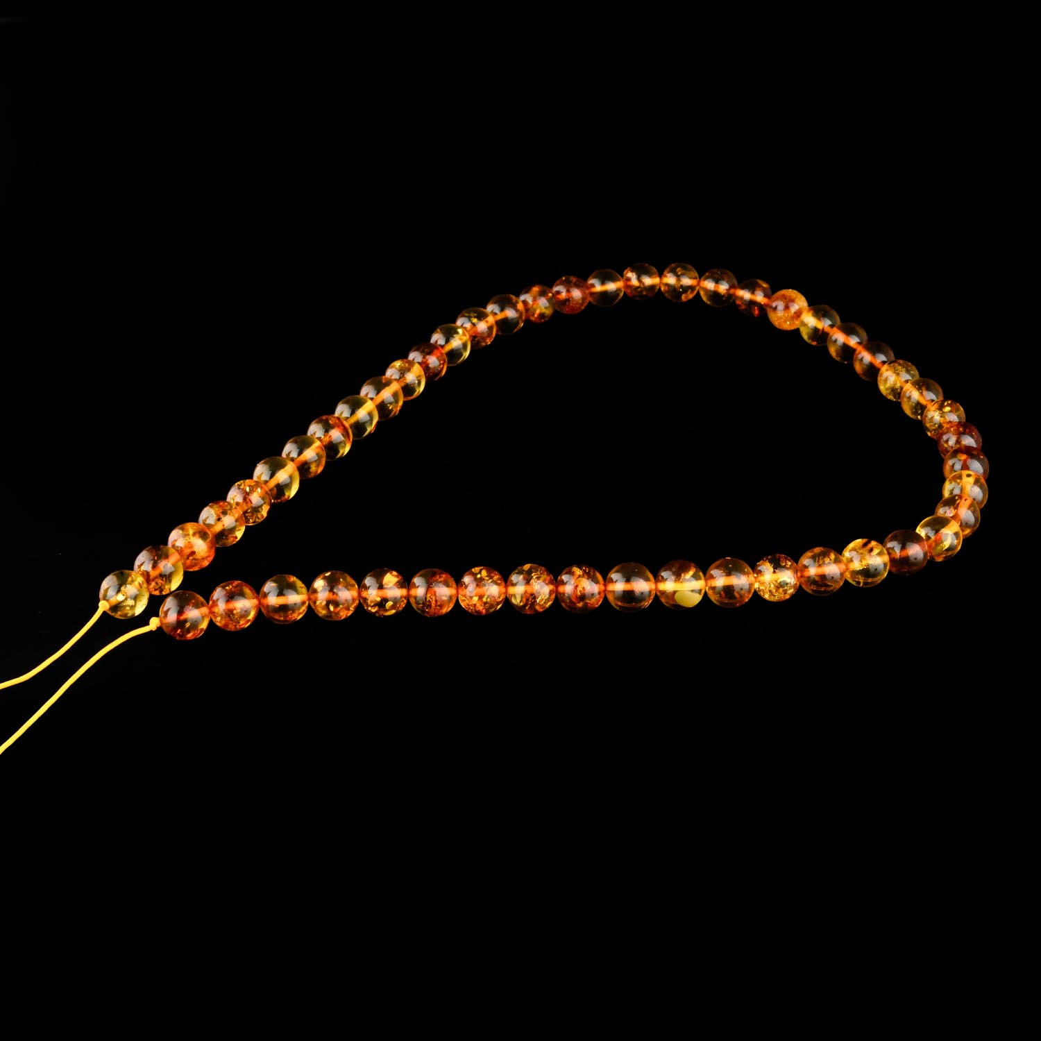 8mm-cognac-bernstein-strang Ein Strang aus 8mm polierten Cognac-Bernsteinperlen auf weißem Display