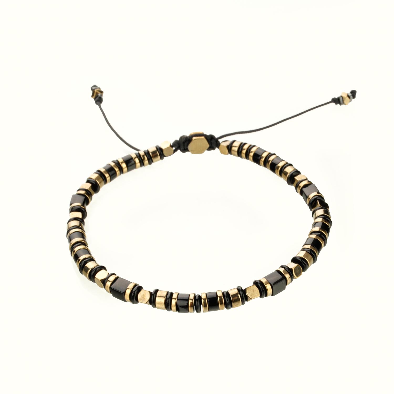 bracelet-macrame-hematite-onyx-dore Bracelet macramé élégant avec perles géométriques en onyx noir et hématite dorée sur cordon réglable, sur surface blanche.