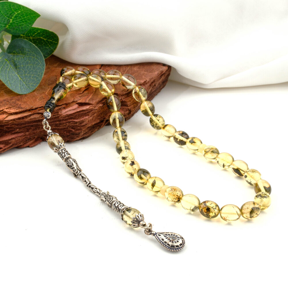 Certified Baltic Green Amber Tesbih with 7.5x9mm sphere-cut beads and 925 silver tassel, on a white surface.