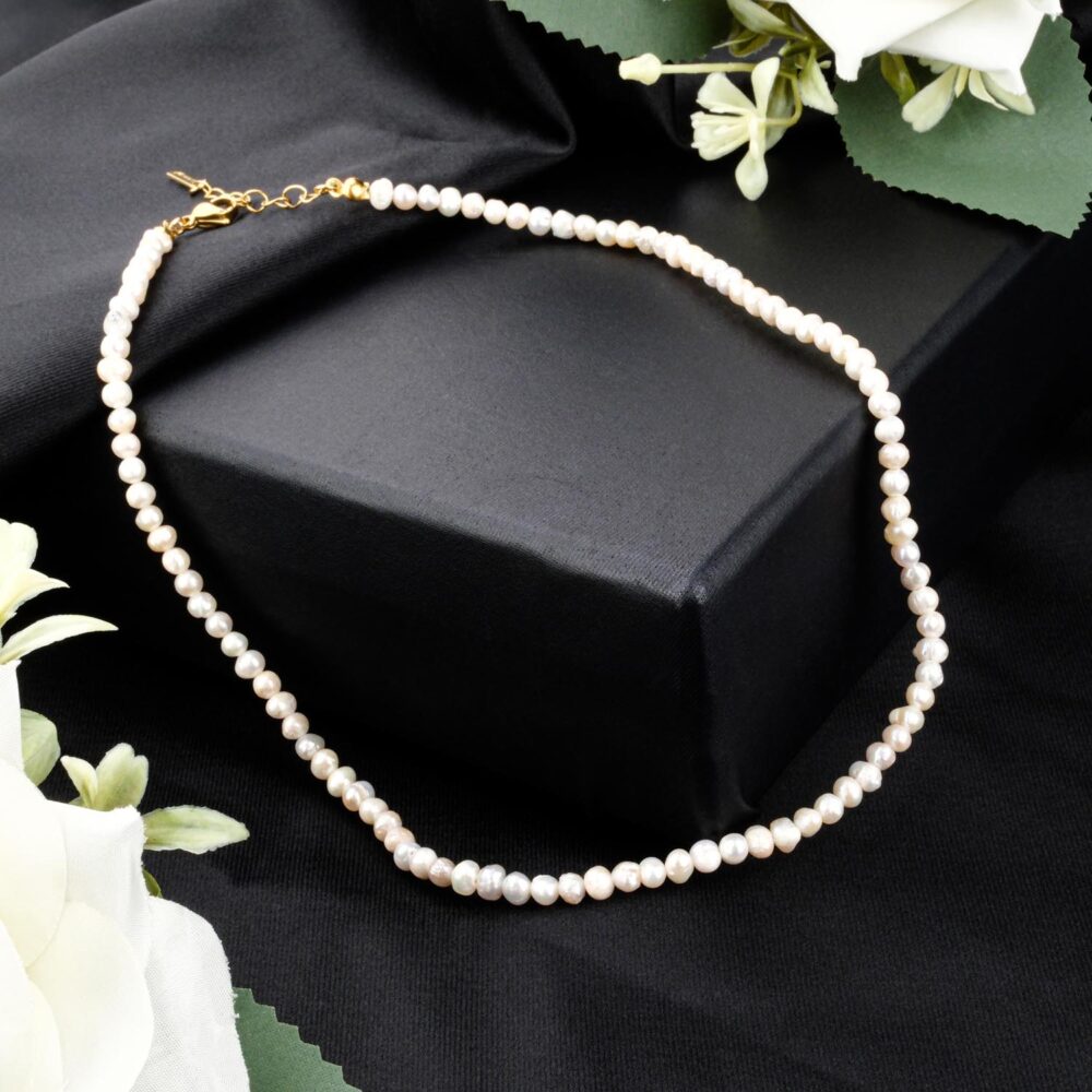 Classic 3-4mm white freshwater pearl strand necklace with gold clasp on black display