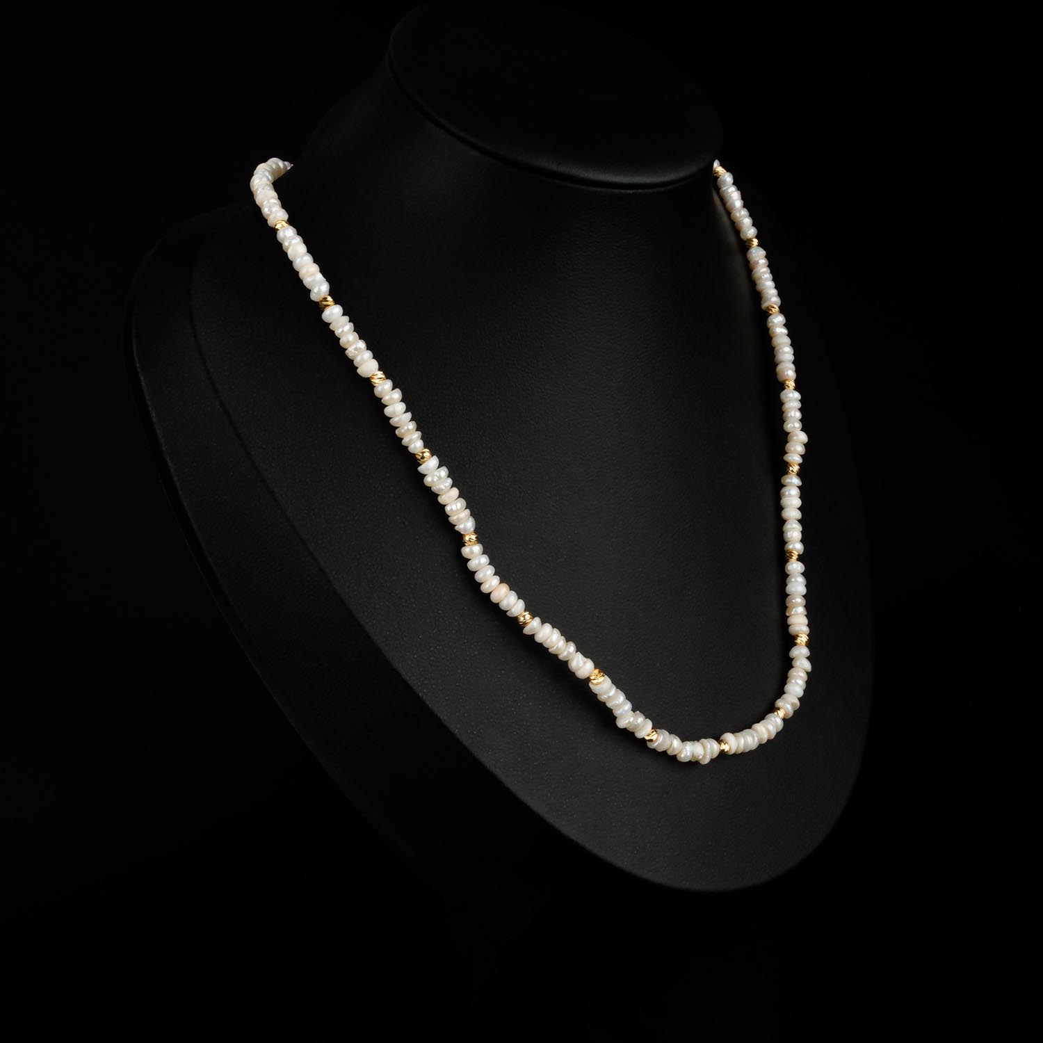 collar-perlas-pequenas-acero-dorado Collar de mini perlas de agua dulce con cuentas de acero dorado sobre fondo negro