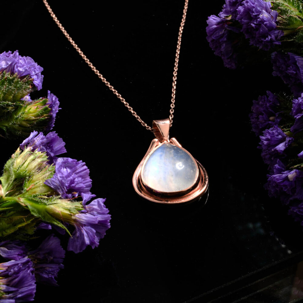 Collar con colgante de lágrima de piedra de luna arcoíris en plata 925 con baño de oro rosa sobre fondo blanco
