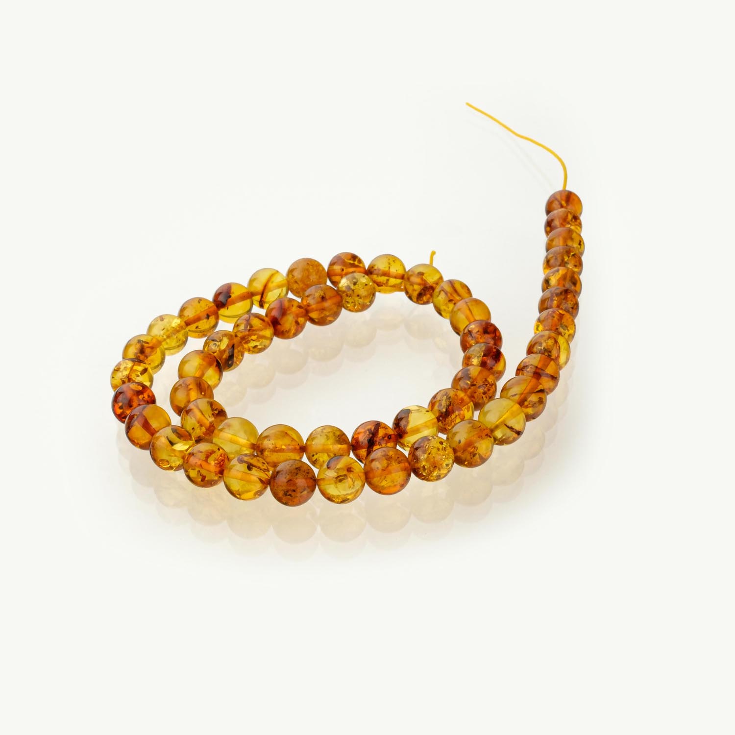 fil-ambre-cognac-8mm Fil de perles d'ambre cognac polies 8mm sur présentoir blanc