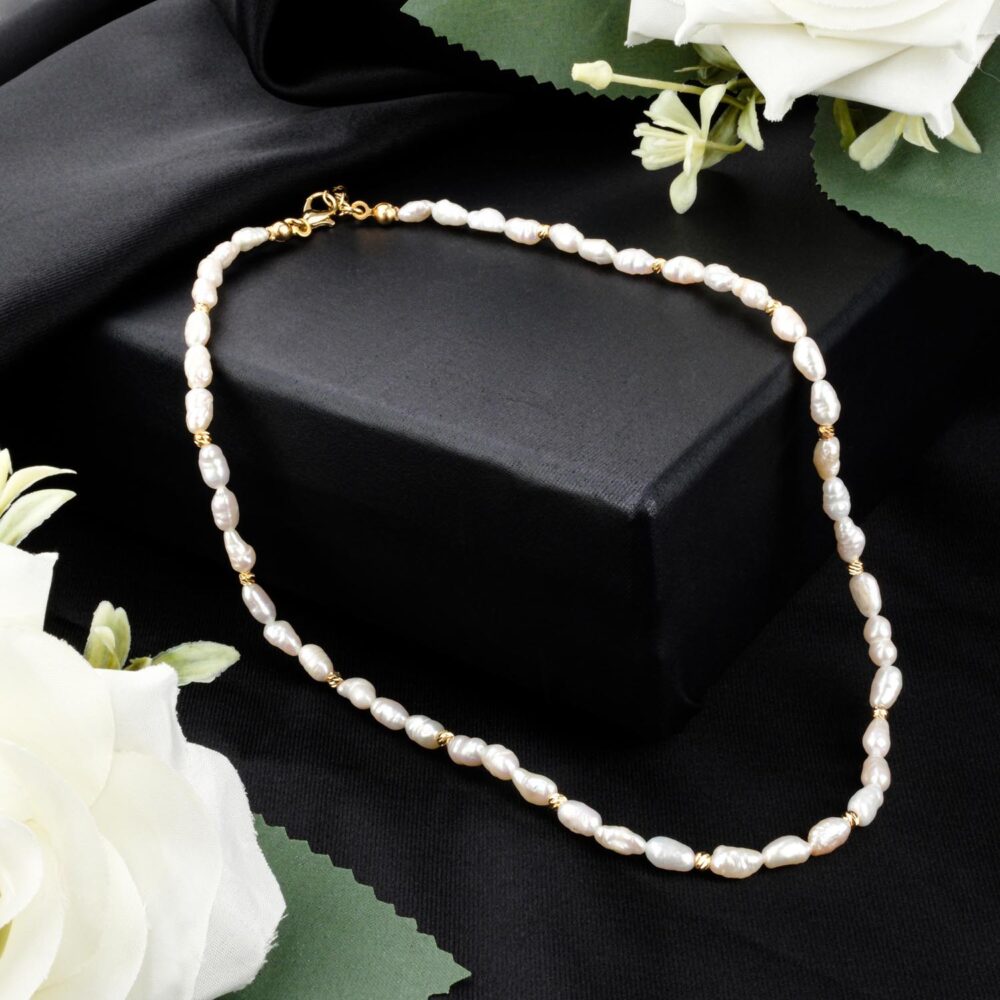 Delicate freshwater rice pearl necklace with gold-tone steel beads on black display
