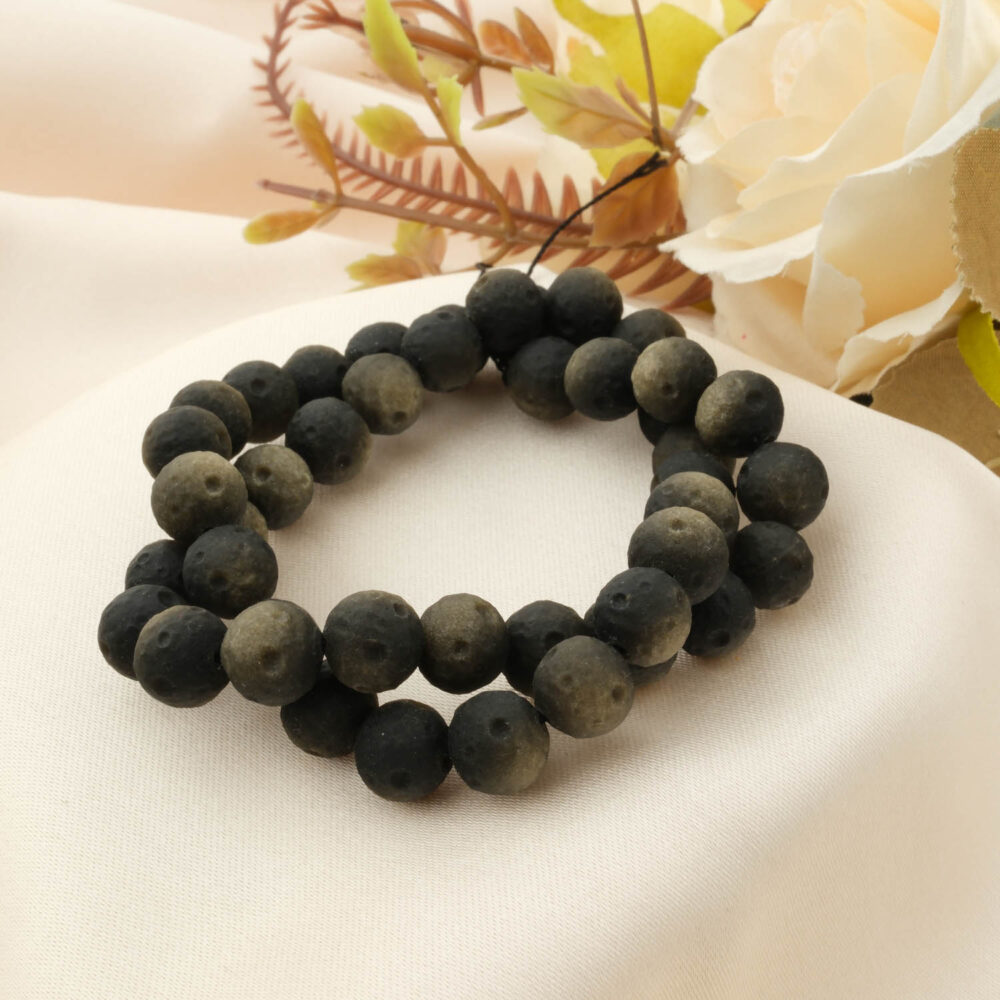 A special frosted (matte) Gold Sheen Obsidian bracelet with 8-9mm beads, styled on a cream satin cloth with a rose.