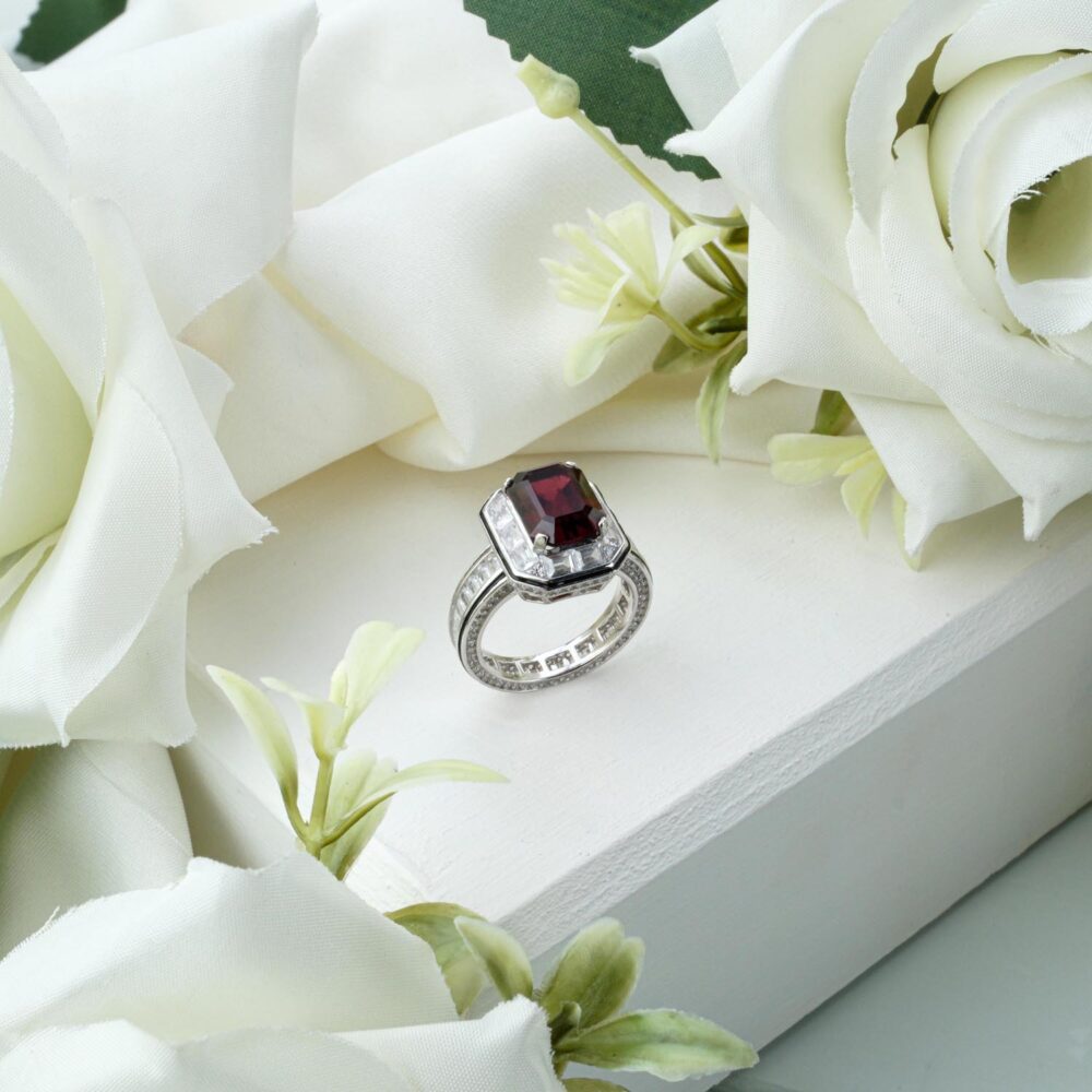 Full eternity ring with round red garnet gemstones in 925 sterling silver on white background