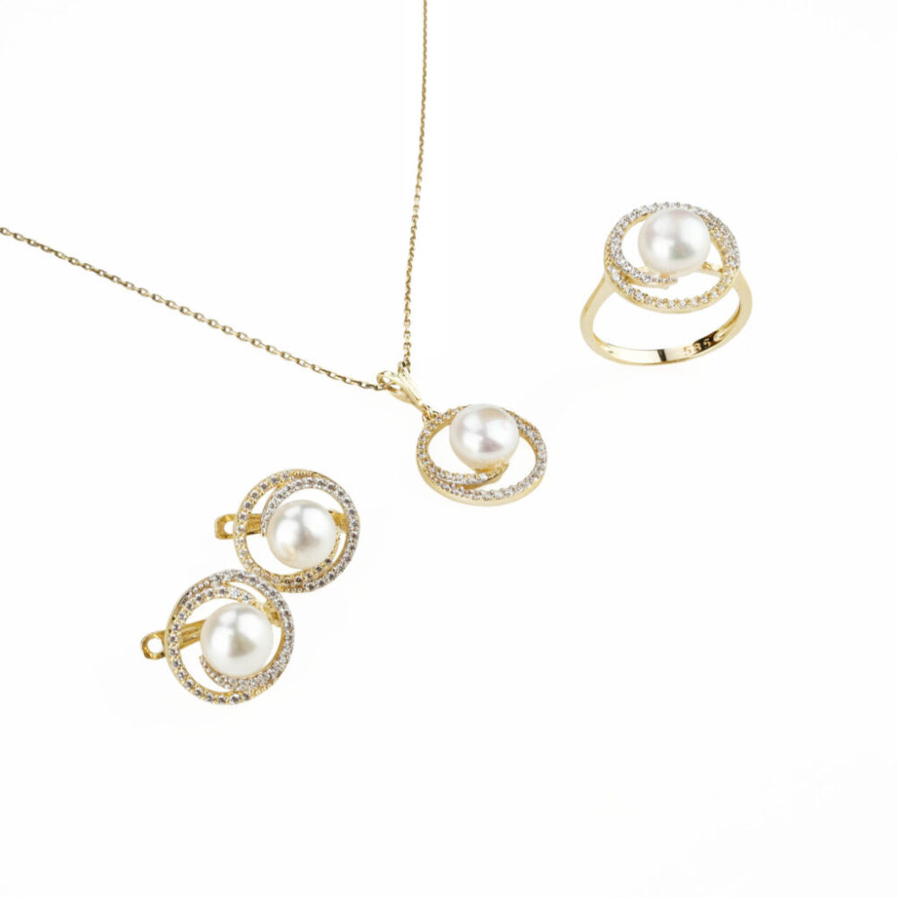 Modelo luciendo un juego completo de joyas de perlas y oro de 14k con diseño floral: collar, pendientes y anillo.