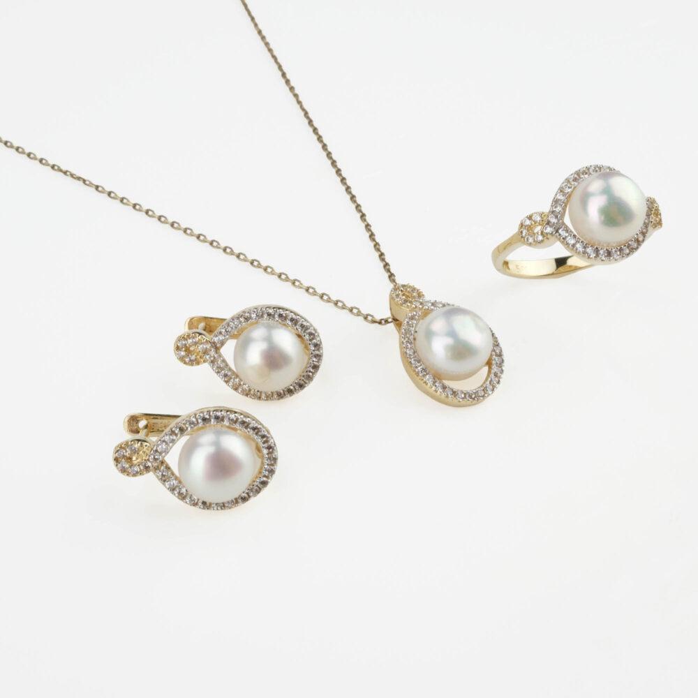 Modelo luciendo un juego completo de joyas de perlas y oro de 14k con halo: collar, pendientes y anillo.