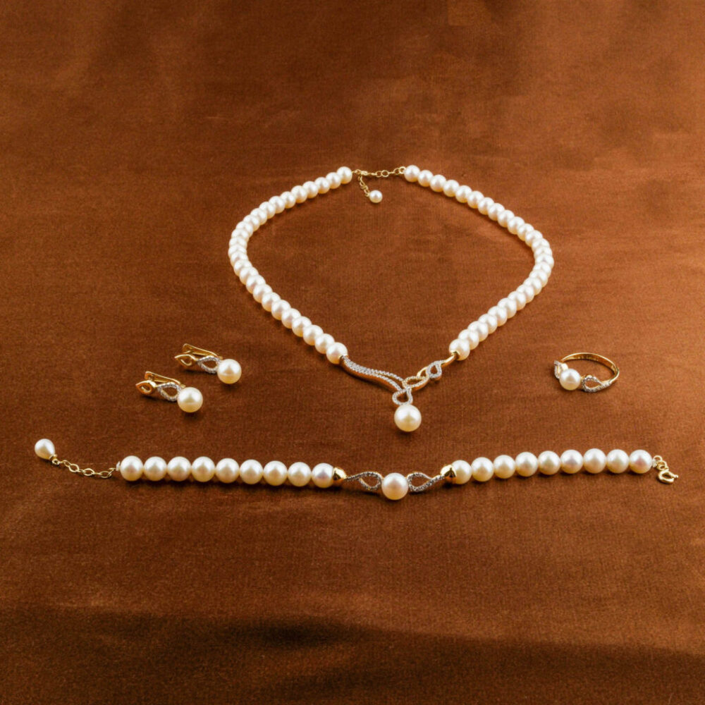 Modelo luciendo un juego completo de joyas de perlas y oro de 14k: collar, pendientes, pulsera y anillo.