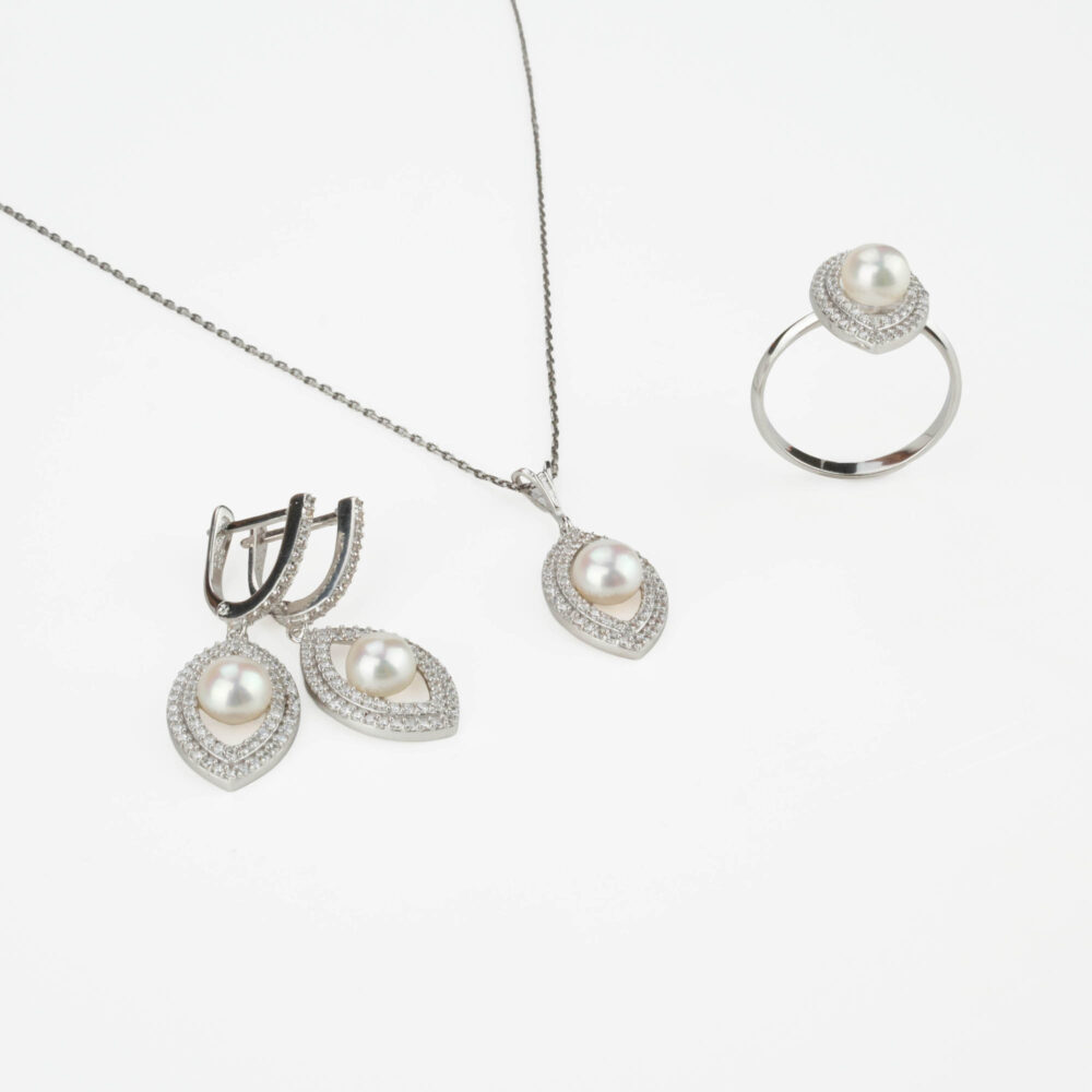 Modelo luciendo un juego completo de joyas de perlas y oro blanco de 14k con halo: collar, pendientes y anillo.