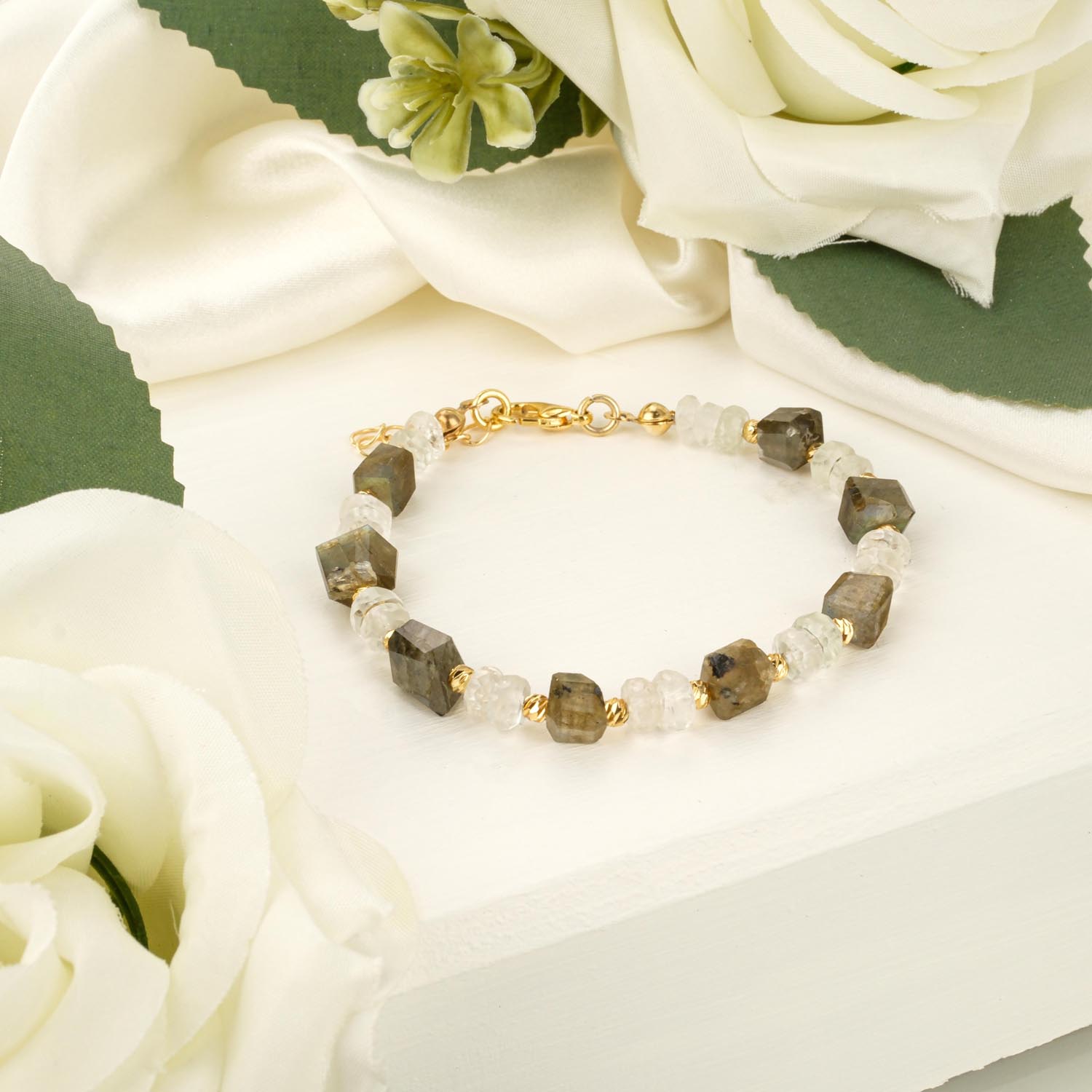 labradorite-moonstone-faceted-bracelet-gold-steel Faceted labradorite and moonstone bracelet with gold-tone steel accents on white