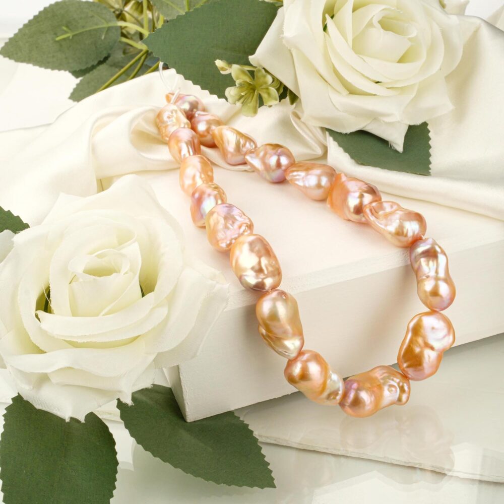 A+ quality large rose baroque pearl strand with high luster on a white display