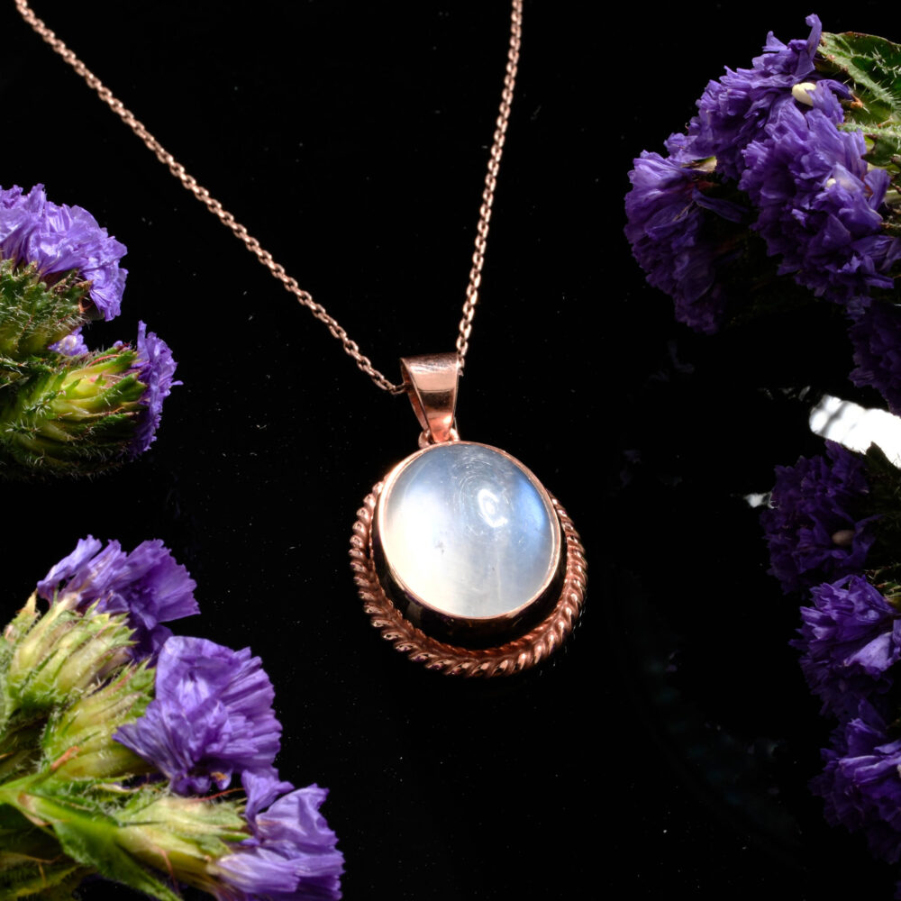Ornate rainbow moonstone round pendant necklace with blue flash in a 925 silver rose gold finish on black