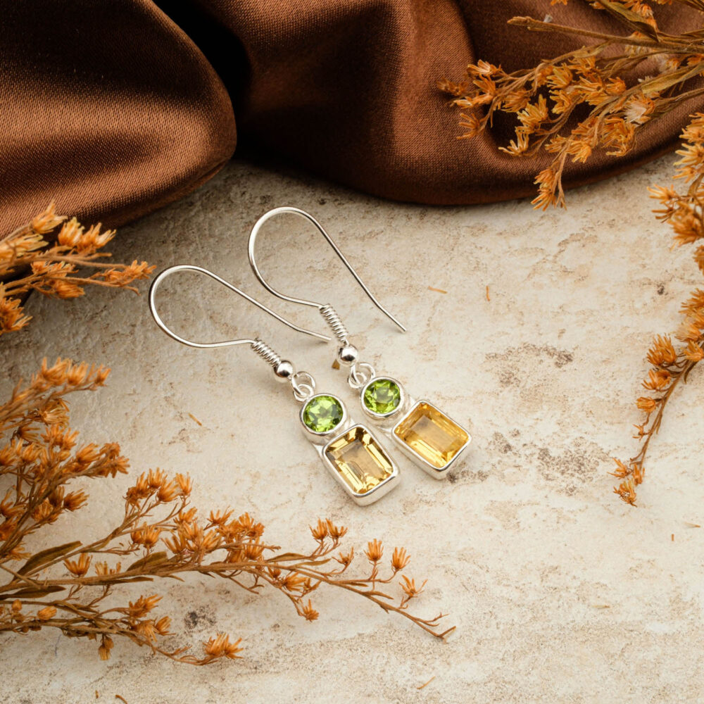 Premium Peridot (round) and emerald-cut Citrine two-stone earrings in 925 sterling silver, on a brown satin background.