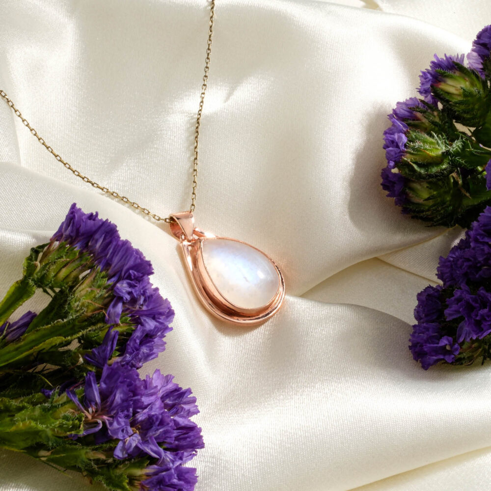 Rainbow moonstone teardrop pendant necklace in 925 sterling silver with a rose gold finish on a white background