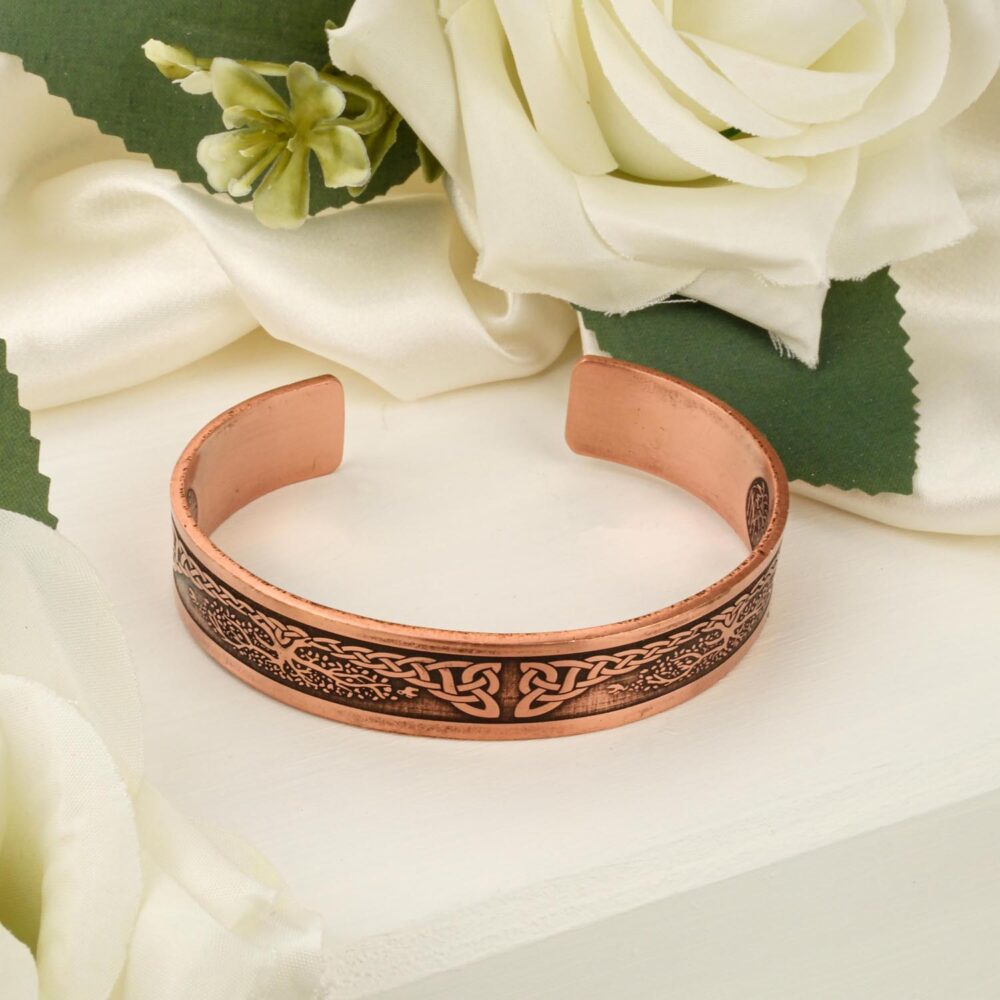 Engraved copper cuff bracelet featuring Tree of Life design on white surface