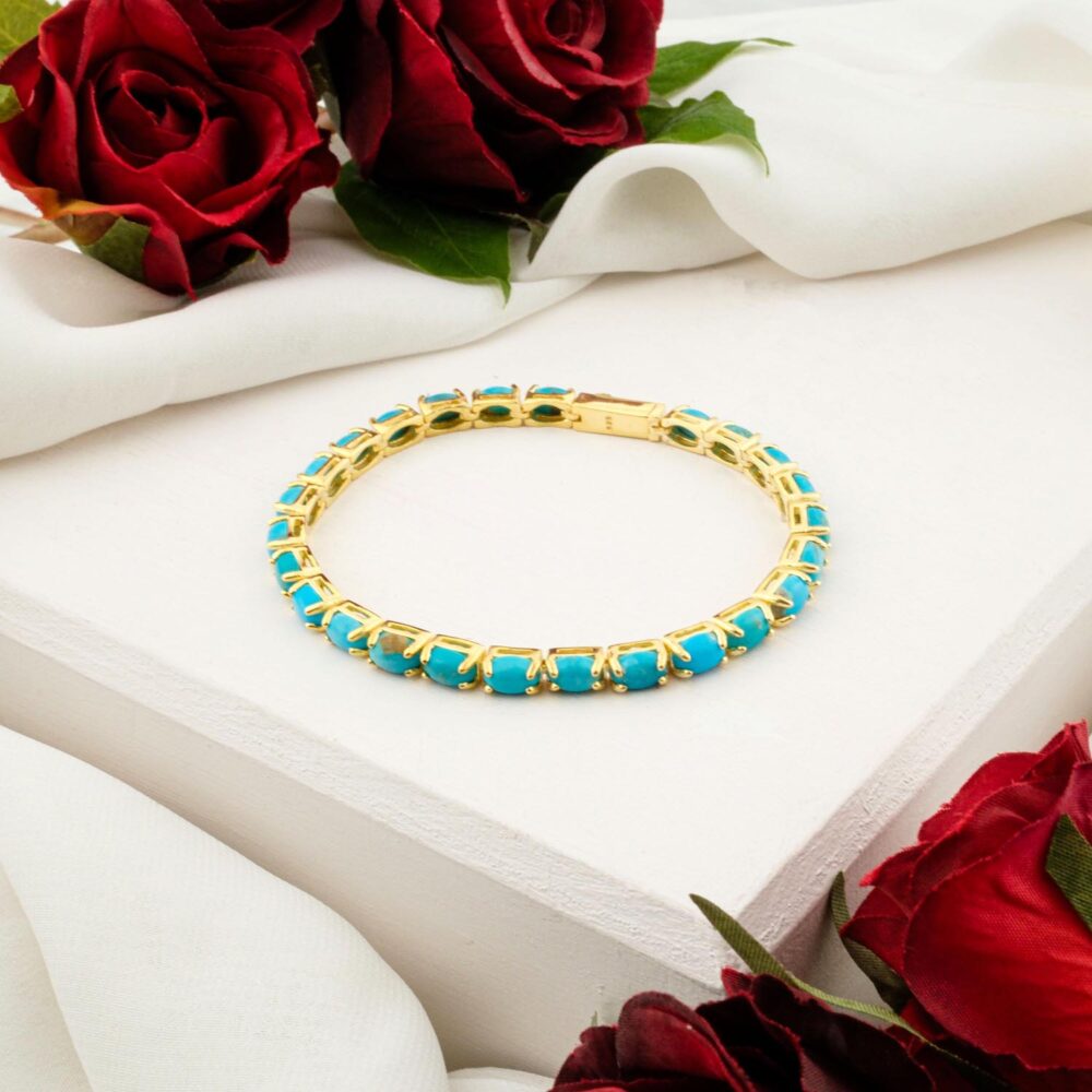 An elegant turquoise tennis bracelet with square-cut stones in a gold-plated sterling silver setting, on a white display.