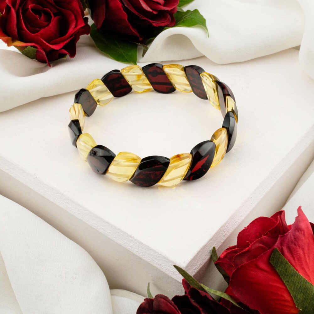 A woven Rolex-style bracelet made of two-tone amber (light and dark), displayed on a white textured surface.