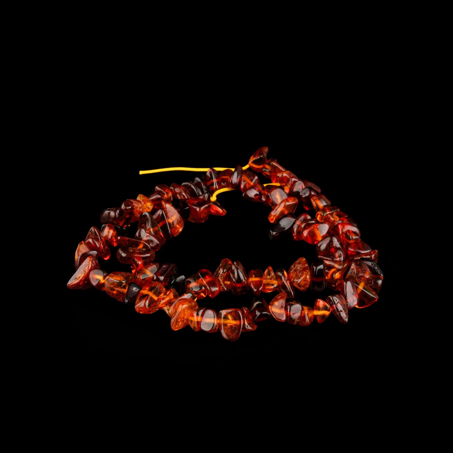 xirdalanmis-kehribar-sap-dizi-konyak Ağ fonda xırdalanmış tünd kəhrəba muncuqlar silsiləsi (qırıq qaya stili)