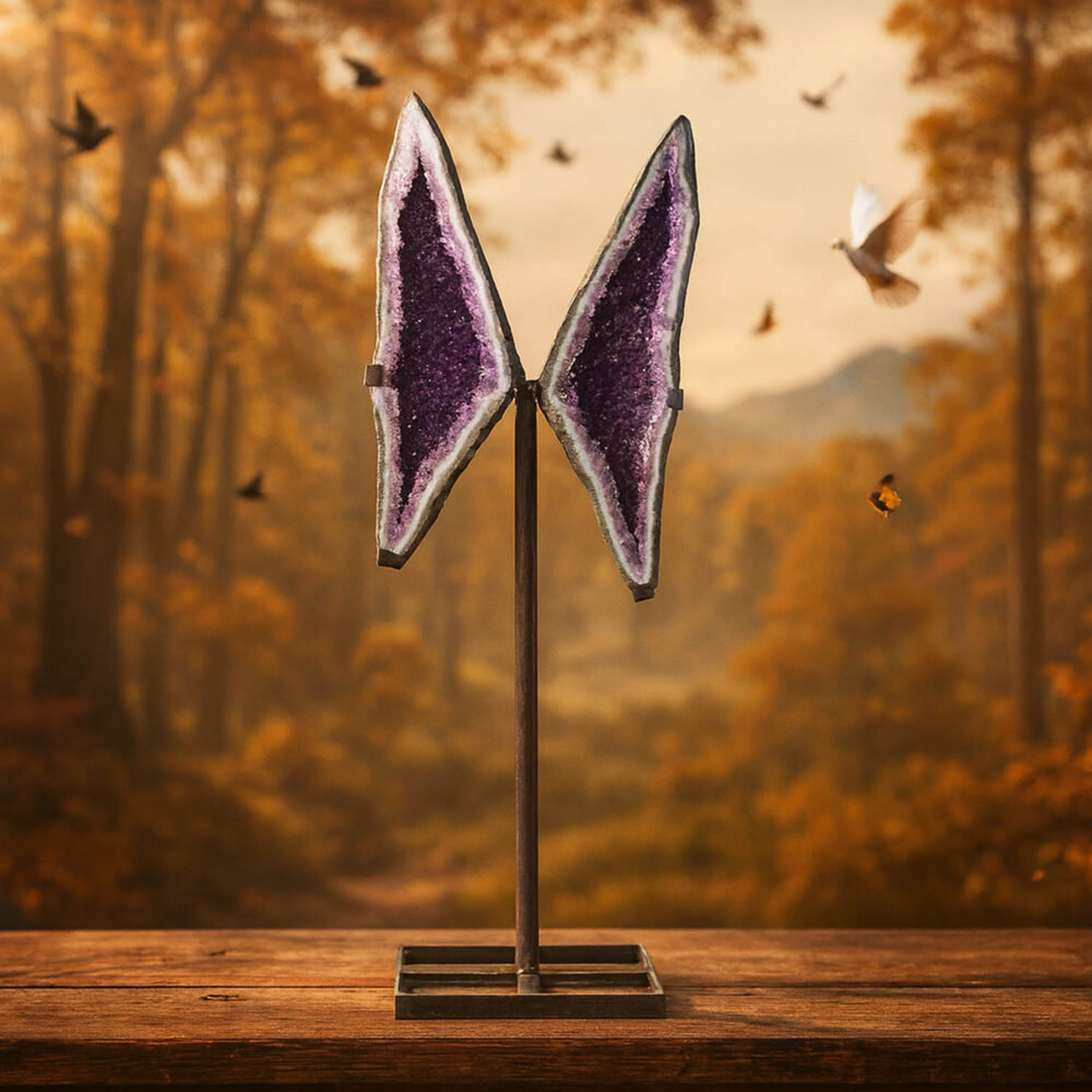 Natural amethyst geode slices shaped like butterfly wings on a metal stand with forest background