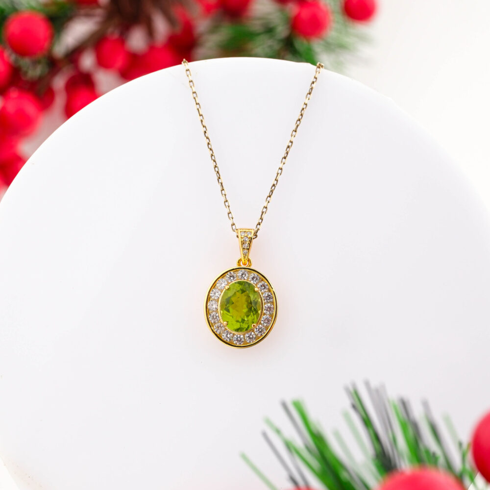 A gold-plated 925 sterling silver necklace featuring a central oval faceted Peridot stone with a crystal halo.