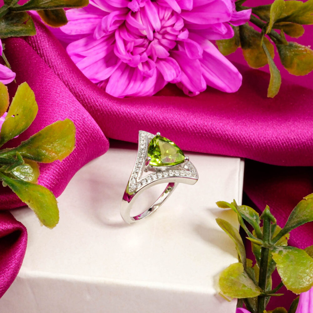 A designer 925 sterling silver ring featuring a trillion-cut Peridot stone with crystal accents on a chevron band.