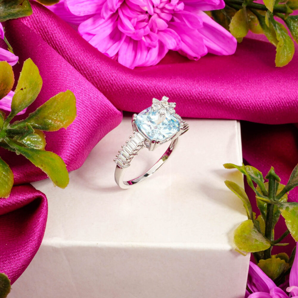 A designer 925 sterling silver ring featuring a cushion-cut Blue Topaz with a unique snowflake detail and baguette band.